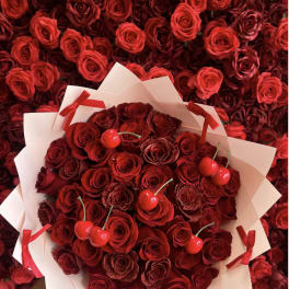 Bouquet of red roses with cherry accents in white wrap