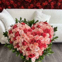 Heart-shaped bouquet of pink and red roses in a vase