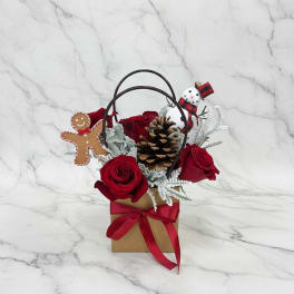Red roses in a gift bag with a pinecone and holiday decorations