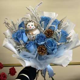 Blue rose bouquet with a small snowman ornament and pinecones