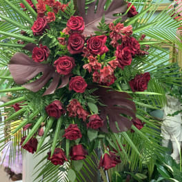 Large arrangement of red roses with tropical leaves and palm fronds