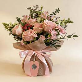 Pink rose and carnation arrangement with white accents in a burlap-wrapped pot tied with a pink satin bow
