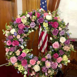 Large floral wreath of pink, purple, and white flowers on a stand