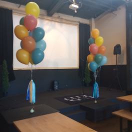 Clusters of colorful balloons on stands in an indoor event space