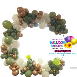 Balloon arch in green, white, and bronze tones