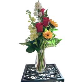 Mixed bouquet in a clear glass vase with red roses and yellow sunflowers