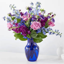 Pink roses and purple-blue flowers in a blue glass vase