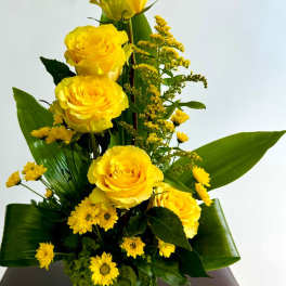 Yellow roses and small yellow daisies in a white vase