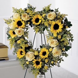 Heart-shaped floral wreath with sunflowers and cream roses on a stand