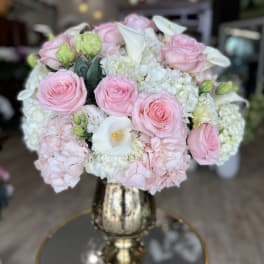 Pink roses and white calla lilies arranged in a gold vase