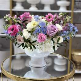 Mixed pastel flower arrangement in a white pedestal vase