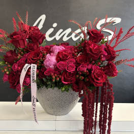 Large red rose arrangement in a silver textured vase with pink ribbon
