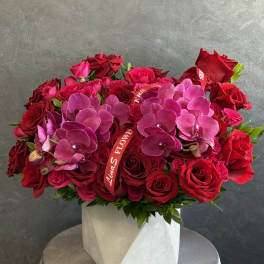 Red roses and pink orchids arranged in a white box