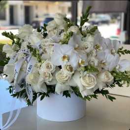 White roses and orchids arranged in a round white box