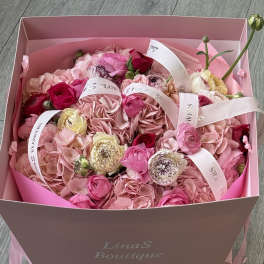 Pink bouquet in a box with roses and hydrangeas tied with white ribbons