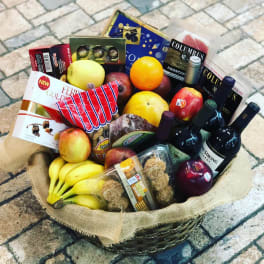 Gift basket with fruit, wine bottles, and packaged snacks