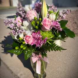 Pink and white mixed bouquet in a glass vase with a pink ribbon