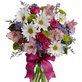 Bouquet of pink roses, daisies, and alstroemeria in a glass vase with a magenta ribbon