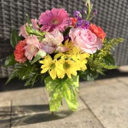 Mixed bouquet of pink, yellow, and red flowers tied with a green polka-dot ribbon