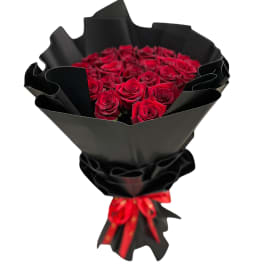 Bouquet of red roses wrapped in black paper with a red ribbon