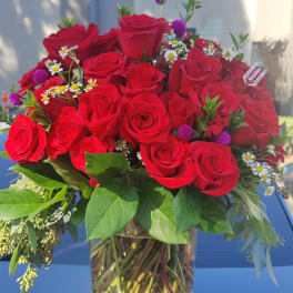 Bouquet of red roses in a clear glass vase with small white daisies