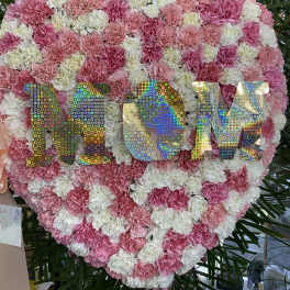 Heart-shaped pink and white carnation display with holographic "MOM" letters