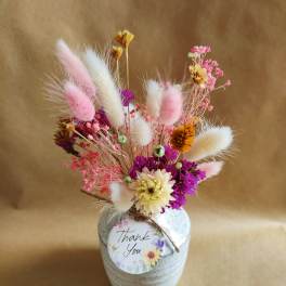 Dried flower arrangement in a white vase with a thank-you tag