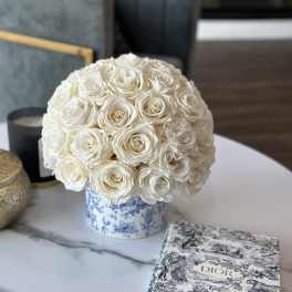 Round bouquet of white roses in a blue-and-white patterned container