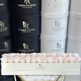Box of pale pink and white roses in a branded hatbox