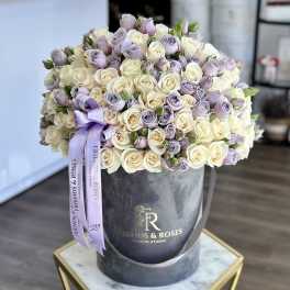 Bouquet of cream and lavender roses in a round hat box with a purple ribbon