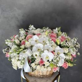 Basket arrangement of pink and white roses with white orchids
