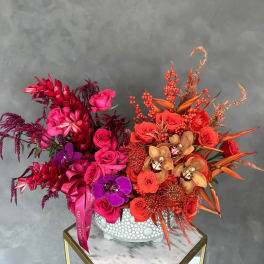Bright red and pink floral arrangement in a white textured vase