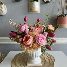 Pink and peach floral arrangement in a white vase