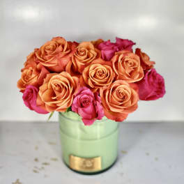 Orange and pink roses arranged in a light green vase