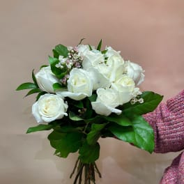 Bouquet of white roses with green foliage and small pink filler flowers