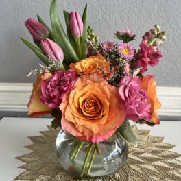 Pink tulips and orange roses arranged in a glass vase