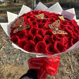 Large bouquet of red roses with gold butterfly accents and a red ribbon
