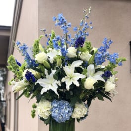 Tall blue and white floral arrangement in a glass vase