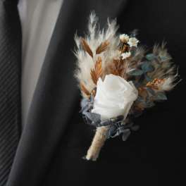 White rose boutonniere with dried accents on a black suit lapel