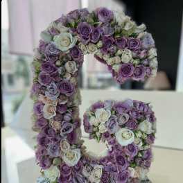 Floral arrangement shaped like the number 5 with purple and white roses