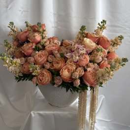 Large peach and cream floral arrangement in a white textured vase