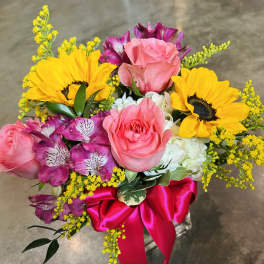 Bouquet of pink roses, sunflowers, and purple alstroemeria with a pink ribbon