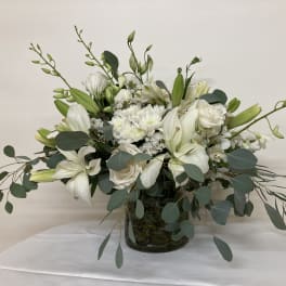 White floral arrangement in a glass vase with long green stems