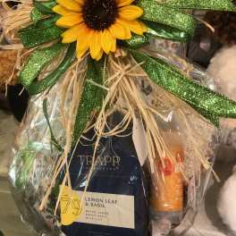 Gift basket with a sunflower topper and candles wrapped in clear cellophane