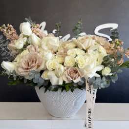 Cream and blush rose arrangement in a white textured vase