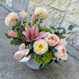 Pink lilies and peach roses in a white vase with a satin ribbon
