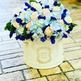 Blue and cream flower arrangement in a round white box