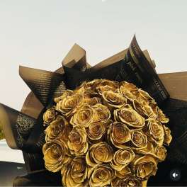 Bouquet of gold-colored roses wrapped in black and brown paper