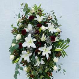 Standing floral spray with white lilies and roses on a black easel