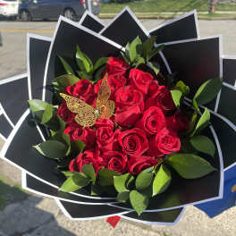 Bouquet of red roses with green foliage and a butterfly accent